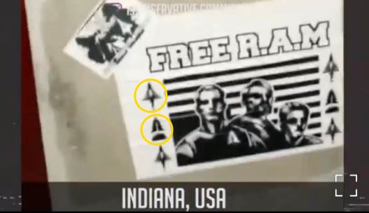 Sticker or poster with bold text "FREE R.A.M" at top in white block letters against a black background. Below, three men's faces appear in silhouette with American flag stripes behind them. White arrow symbols with pine tree motifs are arranged along both sides; two symbols on the left are circled in yellow. A smaller sticker is partially visible in the upper left corner. Text at the bottom reads "INDIANA, USA" in white capital letters on a dark bar.